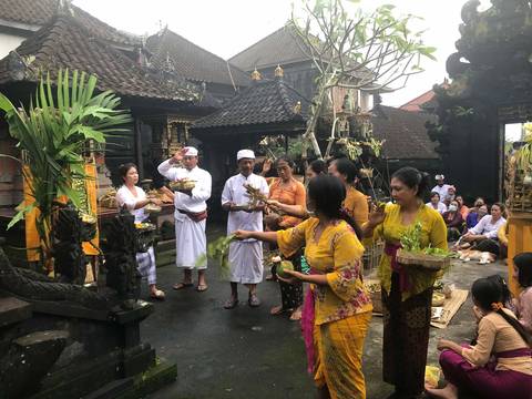 Villagers in temple dress carrying offerings into a family temple courtyard in Sidemen.